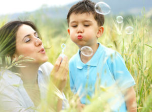 Autism-Community-kid-blowing-bubbles-with-mom