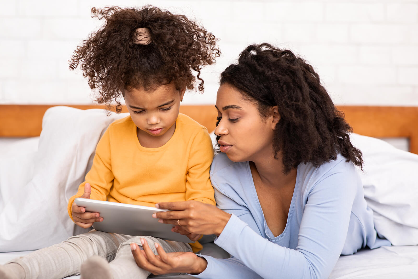 Black Mother Teaching Little Daughter To Use Digital Tablet Lyin