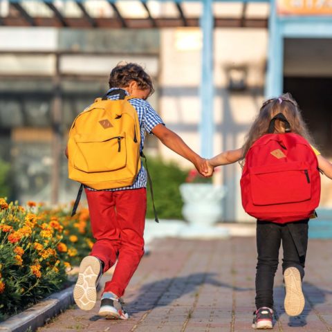 Primary School Pupil. Boy And Girl With Backpacks Walking Down S